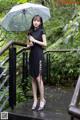 A woman in a black dress holding an umbrella.