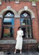A woman standing in front of a brick building.