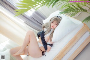 A woman laying on top of a bed next to a plant.