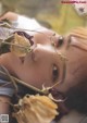 A woman laying on the ground with a bunch of flowers in her mouth.